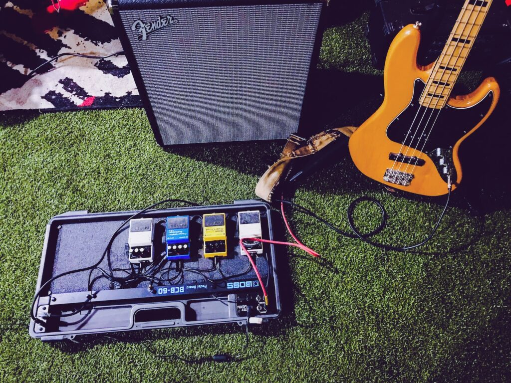 yellow electric bass guitar beside black Fender guitar amplifier